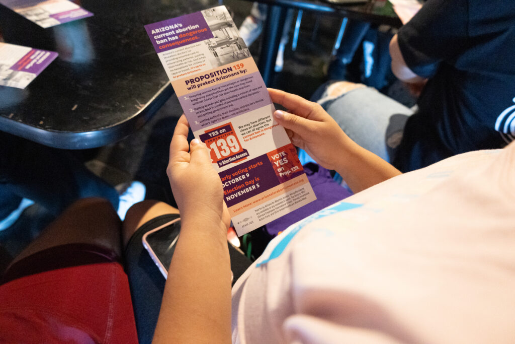 A volunteer holding yes on prop 139 Arizona Abortion Access literature in their hand at Spinelli's Pizza in Tempe, AZ