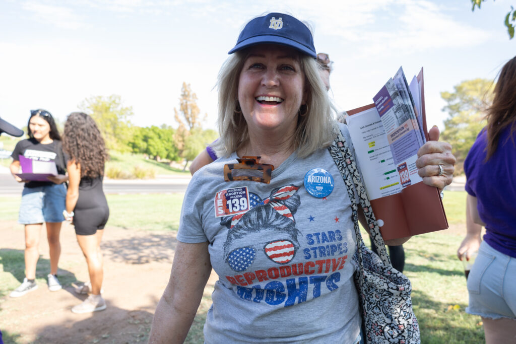 A very enthusiastic woman volunteering for Arizona Abortion Access holding yes on 139 literature before canvassing near Kiwanis Park in Tempe, AZ